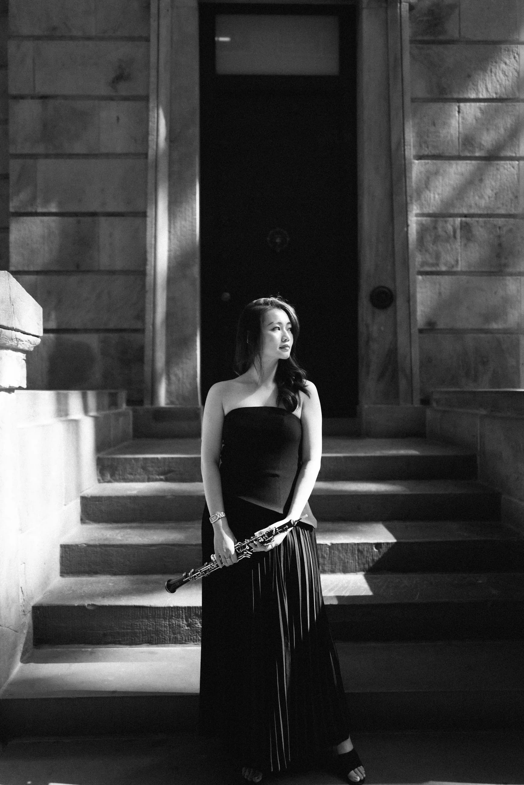 Beverly Wang with her oboe in a stone doorway